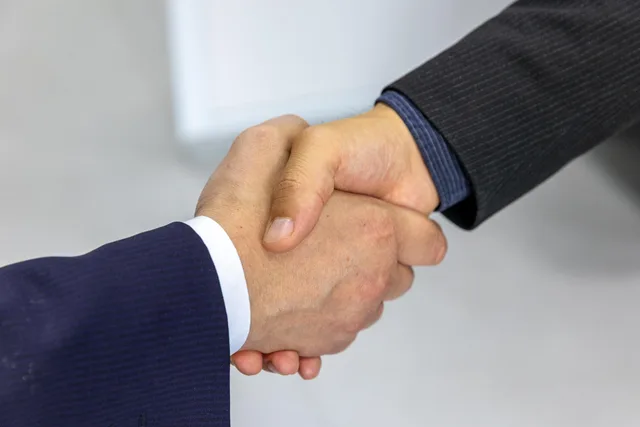 Close-up of two businessmen shaking hands, symbolizing agreement and partnership. Find relevante affiliatepartnere