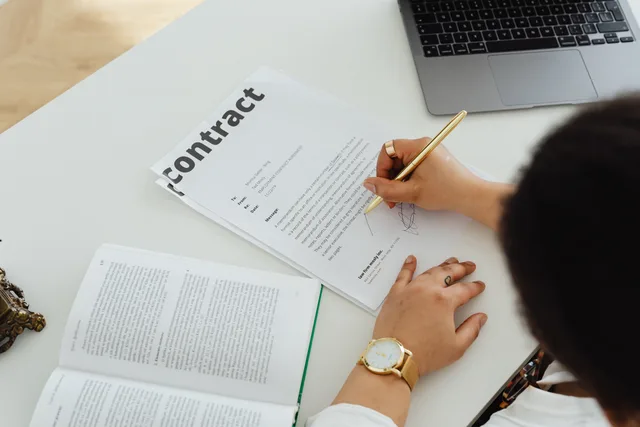 Professional signing a business contract at a modern desk setup for office work. Regler for affiliateprogrammer